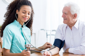 caregiver checking blood pressure of old man