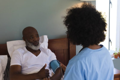 adult woman checking blood pressure of senior man